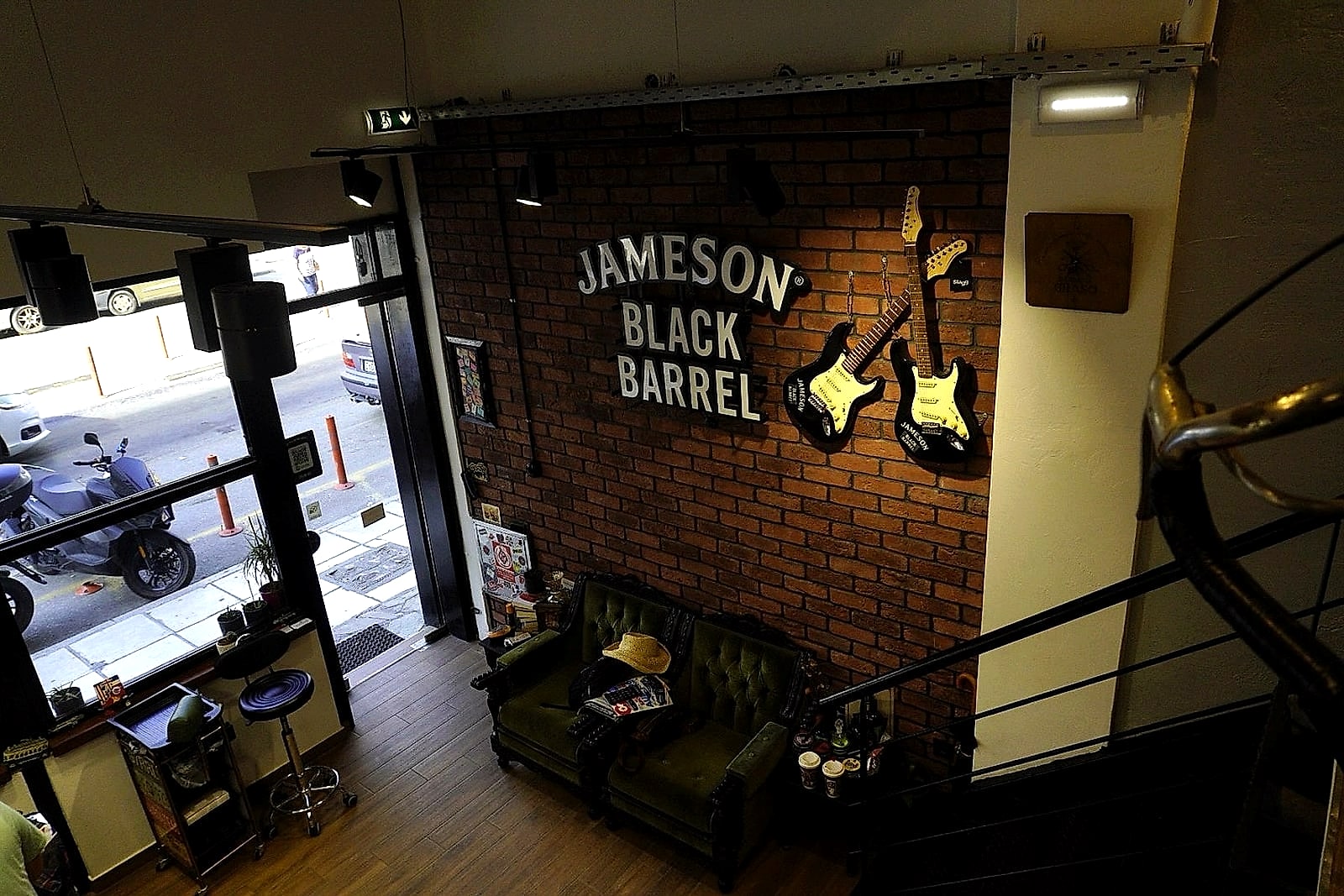 Ο χώρος της Barberia Graso: ο τοίχος Jameson Black Barrel με τις δύο κιθάρες και ο βελούδινος Chesterfield καναπές